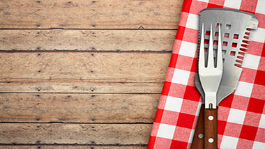 wood table bbq utensils and red and white check napkin